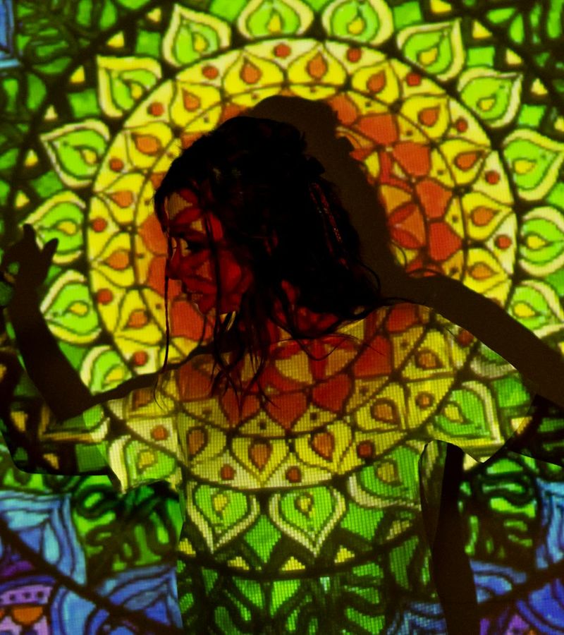 Woman in a balanced yoga pose against a dark background with copper light.